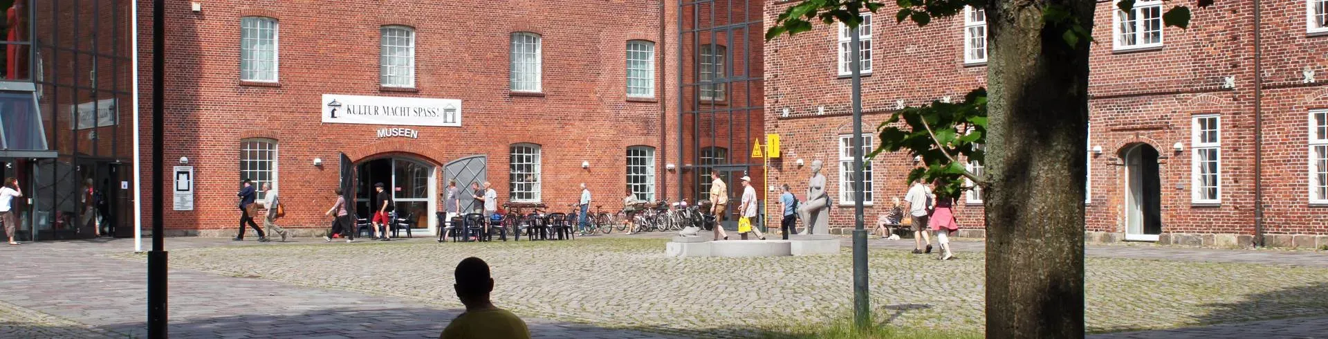 Der Innenhof des Kulturzentrums im Hohen Arsenal mit dem Eingang zu den Museen, Besucher und Fahrräder vor der Backsteinfassade.