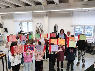Schulkinder halten im Druckmuseum ihre selbst gestalteten Bücher hoch.