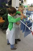 Zwei Kinder hängen geschöpfte Papierbögen auf einen Wäscheständer.