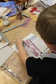 Ein Kind arbeitet mit Werkzeug an einem Buchdeckel.
