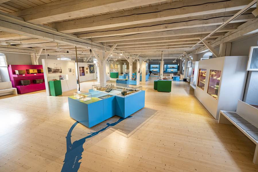 Heller Saal des Historischen Museums mit blauen Vitrinen und dem Verlauf des Kanals als Linie im Holzboden.