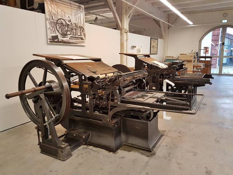 Schnellpresse mit großem Schwungrad im Maschinensaal des Druckmuseums.